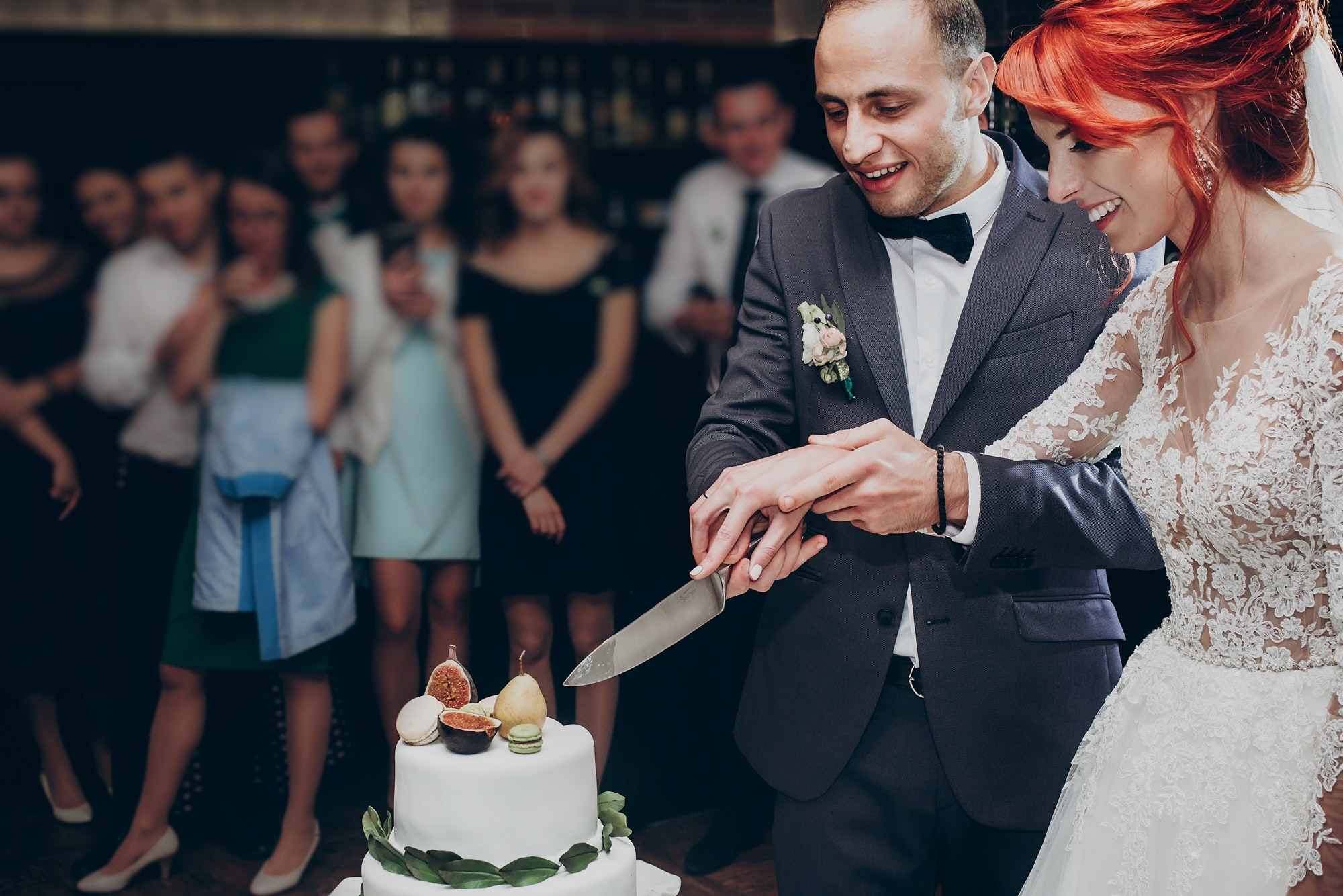 Happy wedding couple cutting together wedding cake